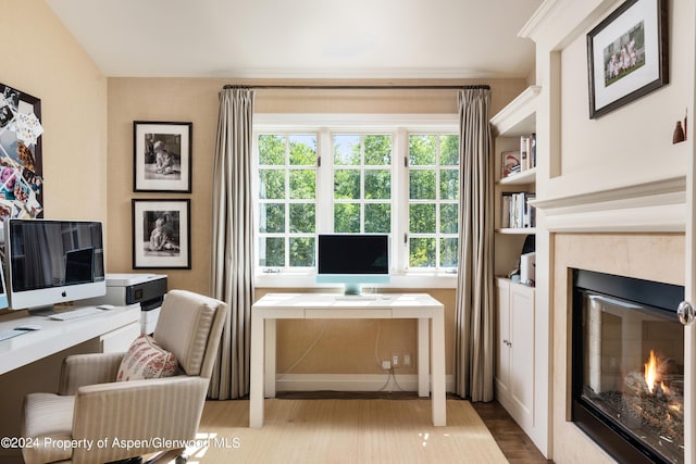 home office with a high end fireplace and light wood-type flooring