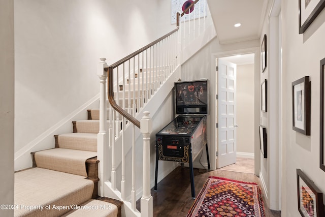 stairs with hardwood / wood-style floors and ornamental molding