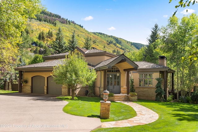 view of front of property featuring a mountain view, a garage, and a front lawn