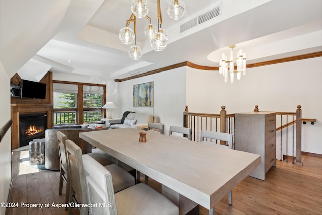 dining room with hardwood / wood-style flooring, a tray ceiling, and a notable chandelier