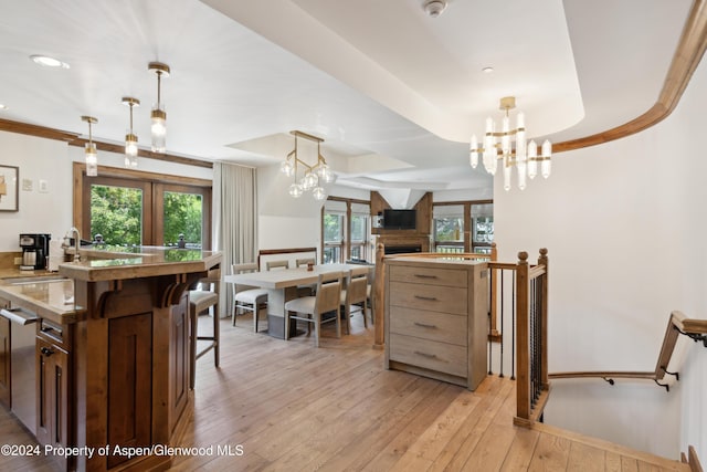 kitchen with decorative light fixtures, light hardwood / wood-style floors, sink, and an inviting chandelier