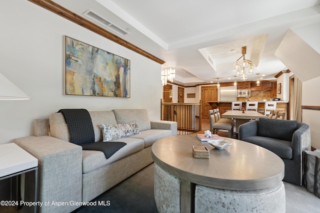 living room featuring a chandelier and a raised ceiling