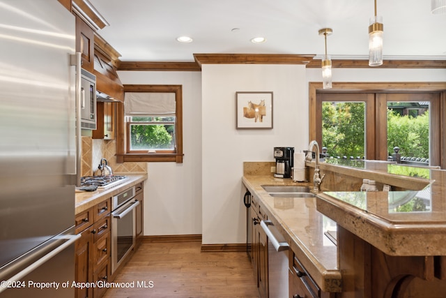 kitchen with sink, stainless steel appliances, backsplash, pendant lighting, and ornamental molding