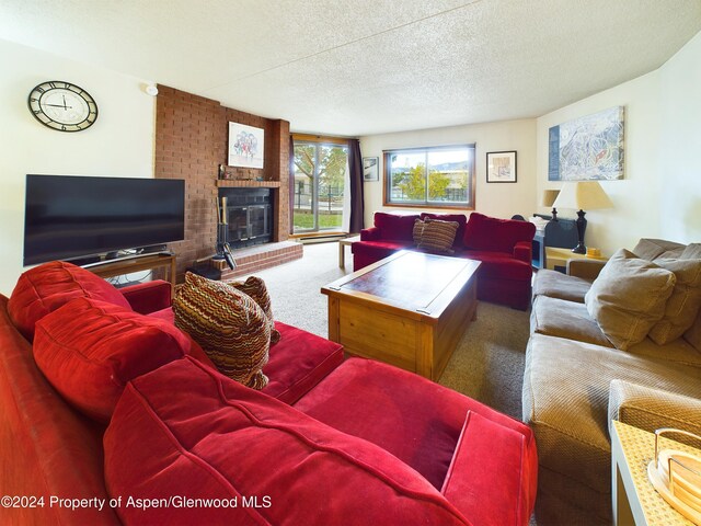 carpeted living room featuring a textured ceiling and a brick fireplace