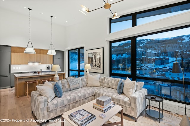 living room featuring a mountain view, light hardwood / wood-style floors, sink, and high vaulted ceiling