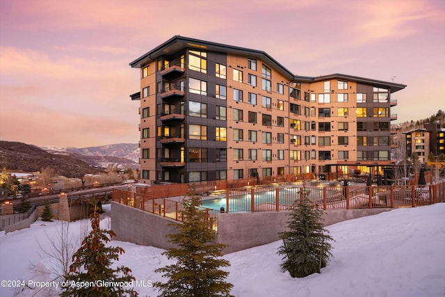 snow covered property featuring a mountain view and a community pool