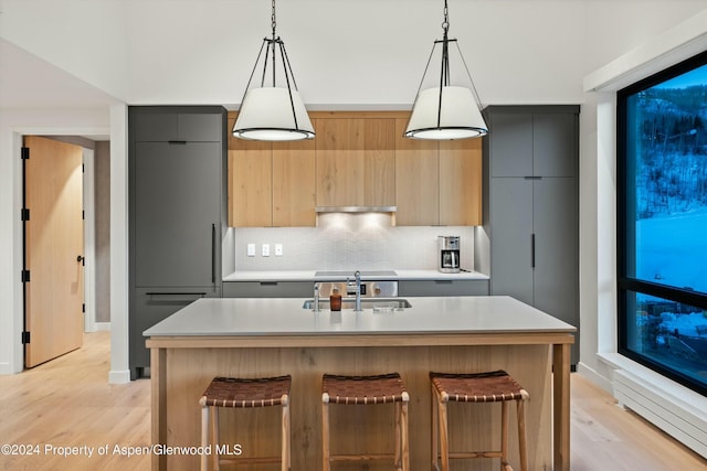 kitchen featuring a kitchen bar, pendant lighting, a kitchen island with sink, and sink