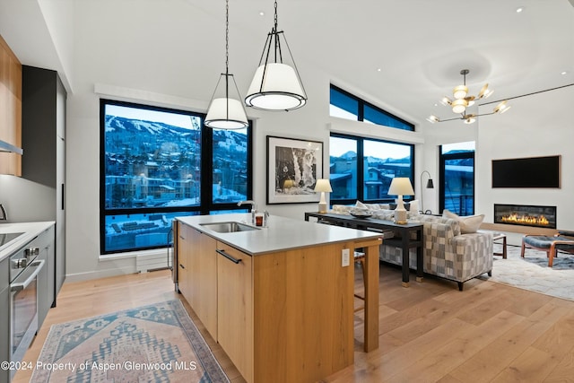 119 Wood Rd Unit 601, Snowmass Village, CO 81615 - kitchen featuring modern cabinets, stainless steel oven, light wood-style flooring, a chandelier, and open floor plan