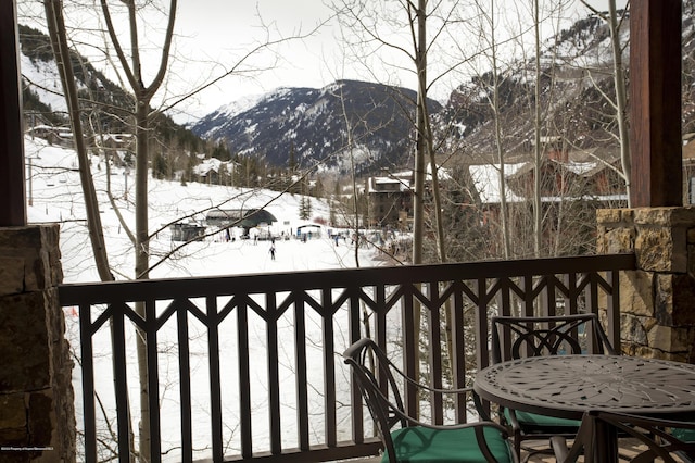 snow covered back of property featuring a mountain view