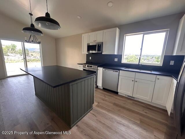 326 W 30th St, Rifle, CO 81650 - kitchen with stainless steel appliances, dark countertops, a sink, light wood-style flooring, and decorative backsplash