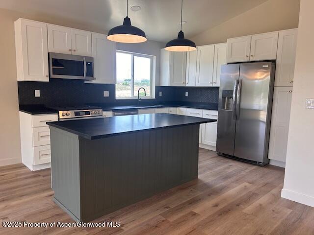 326 W 30th St, Rifle, CO 81650 - kitchen with appliances with stainless steel finishes, a sink, dark countertops, white cabinetry, and tasteful backsplash