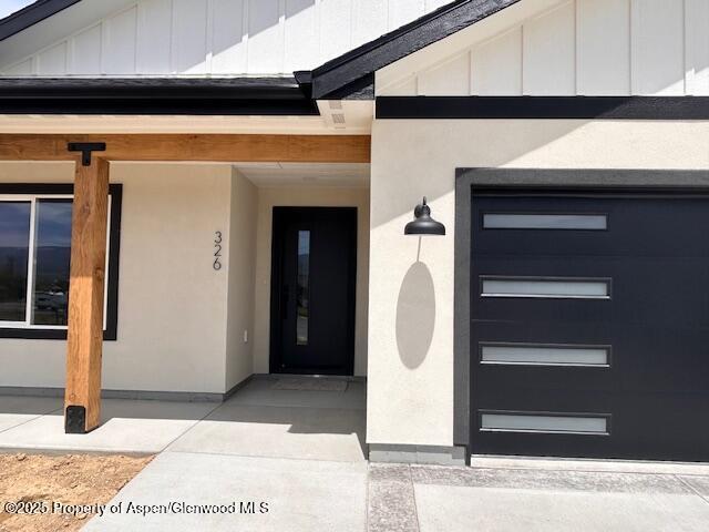 326 W 30th St, Rifle, CO 81650 - doorway to property with board and batten siding, a garage, and stucco siding