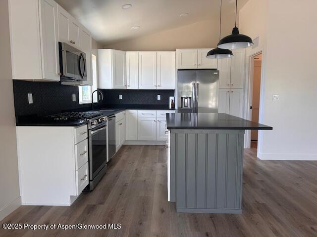 326 W 30th St, Rifle, CO 81650 - kitchen featuring stainless steel appliances, dark countertops, wood finished floors, and vaulted ceiling