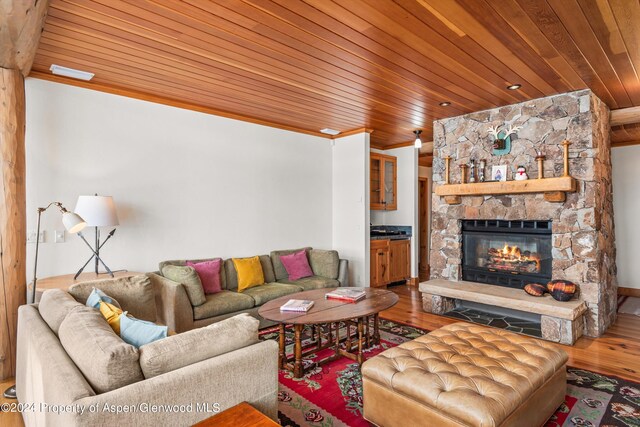 living room featuring wood ceiling, crown molding, a fireplace, and hardwood / wood-style floors