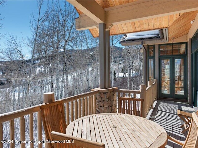 snow covered deck featuring a mountain view and french doors