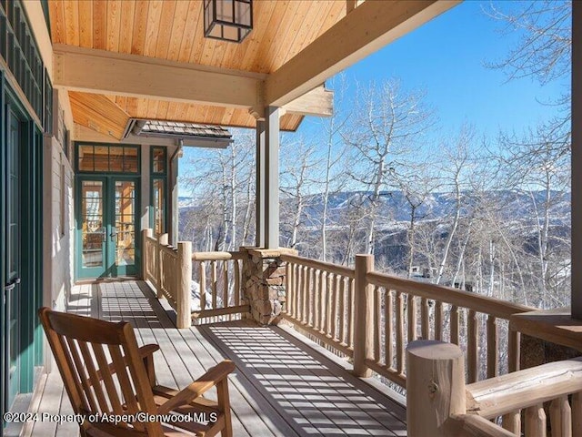 snow covered deck with a mountain view and french doors