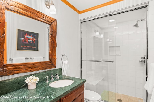 bathroom featuring vanity, toilet, a shower with shower door, and crown molding