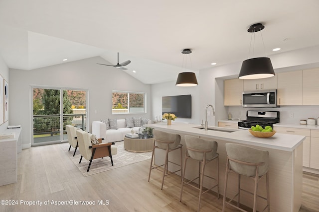 kitchen with stainless steel appliances, sink, pendant lighting, light hardwood / wood-style floors, and lofted ceiling