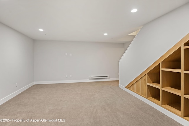 spare room with built in features, light carpet, and a baseboard radiator