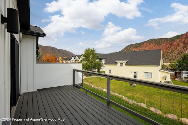 wooden deck featuring a mountain view and a yard