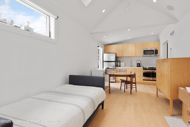 bedroom with stainless steel refrigerator, high vaulted ceiling, and light hardwood / wood-style flooring