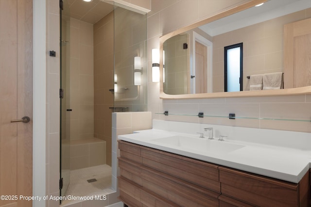 bathroom with vanity, an enclosed shower, tile walls, and tasteful backsplash