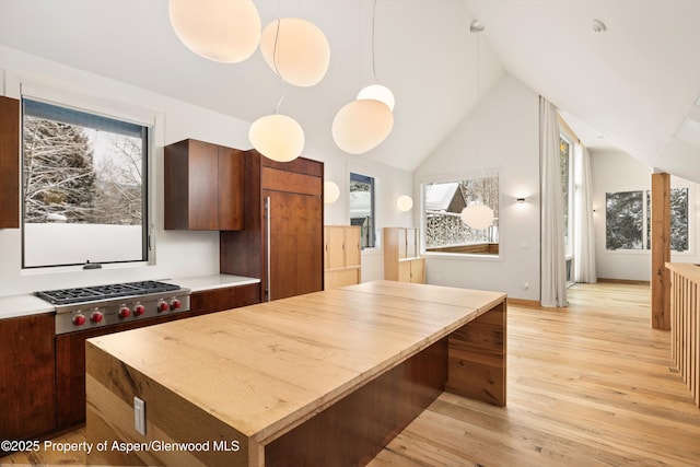 kitchen featuring stainless steel gas cooktop, a center island, light hardwood / wood-style floors, hanging light fixtures, and lofted ceiling