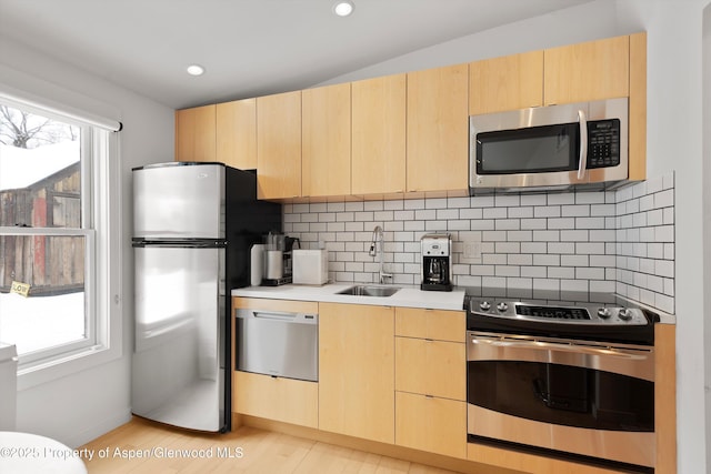 kitchen featuring appliances with stainless steel finishes, tasteful backsplash, a wealth of natural light, sink, and light brown cabinets