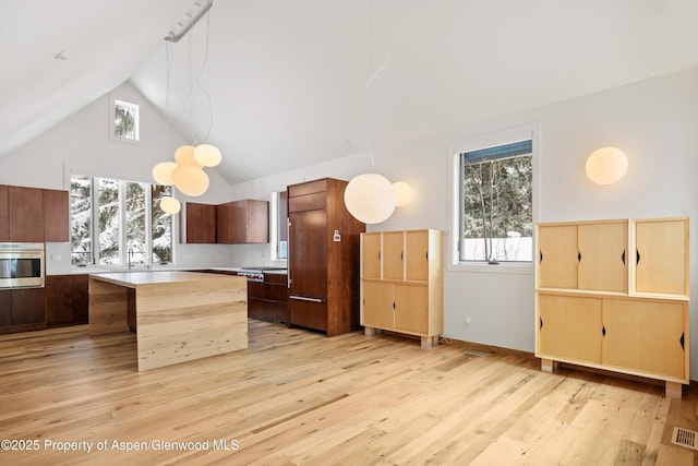 kitchen featuring pendant lighting, a breakfast bar, light wood-type flooring, wall oven, and a kitchen island