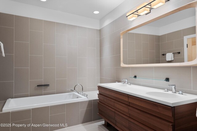 bathroom featuring tasteful backsplash, vanity, a relaxing tiled tub, and tile walls