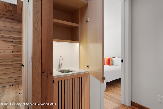 interior space featuring wooden walls, sink, and light wood-type flooring