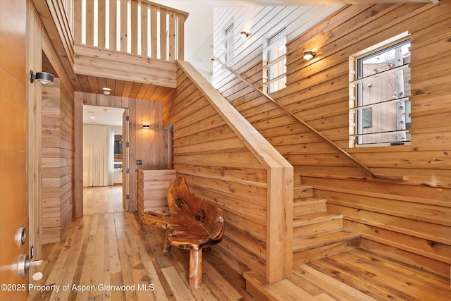 stairs featuring wood walls, wood-type flooring, and a towering ceiling