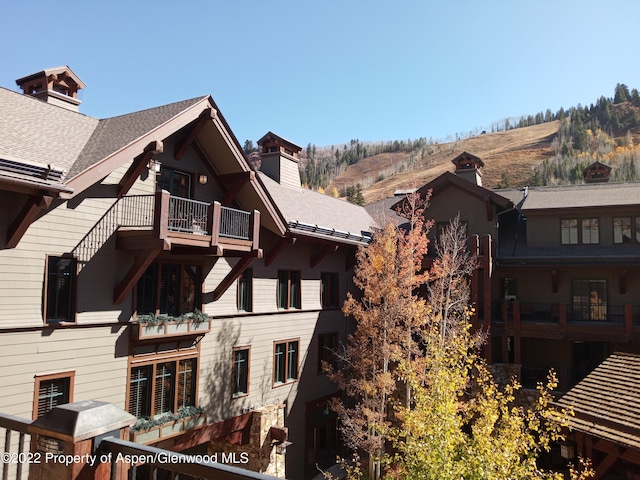 back of property featuring a mountain view and a balcony