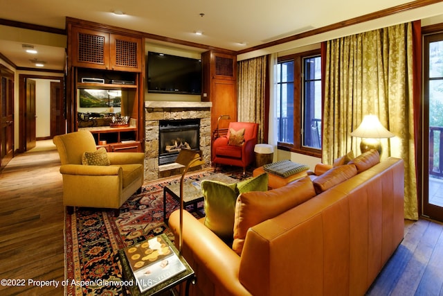 living room featuring hardwood / wood-style flooring, a stone fireplace, and ornamental molding