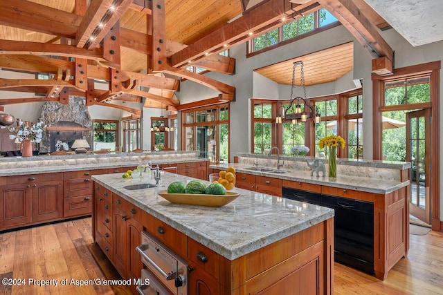 kitchen featuring light stone counters, a spacious island, sink, and hanging light fixtures