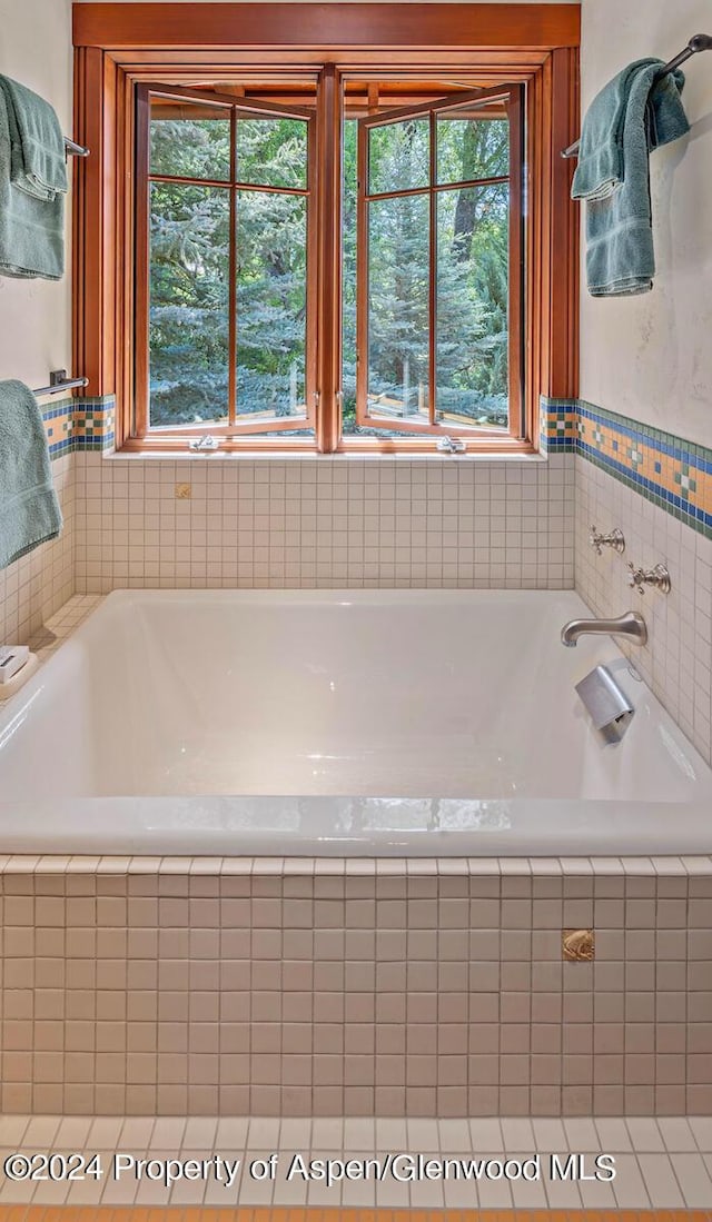 bathroom with tiled bath and a wealth of natural light