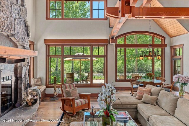 living room with beam ceiling, a stone fireplace, high vaulted ceiling, and hardwood / wood-style flooring