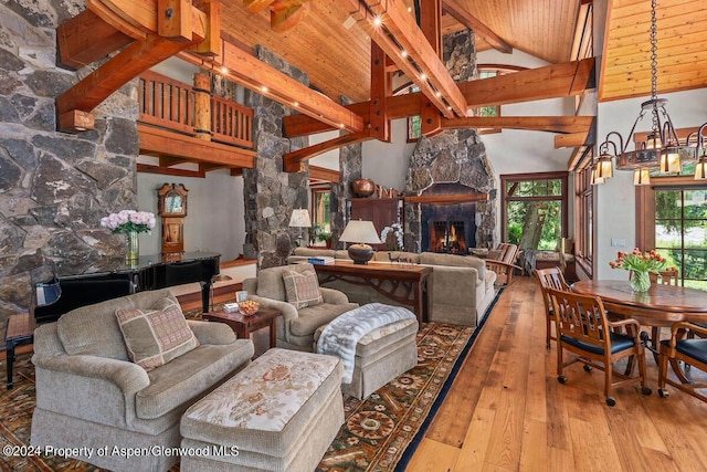 living room featuring a stone fireplace, beamed ceiling, high vaulted ceiling, and light wood-type flooring