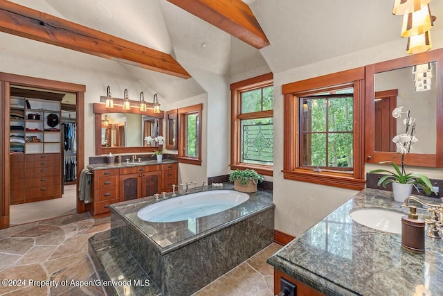 bathroom with vaulted ceiling with beams, vanity, and tiled tub