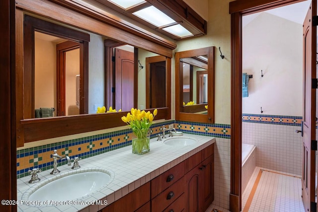 bathroom with tile patterned floors, vanity, a bathtub, and tile walls