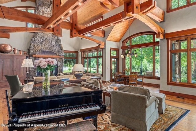 living room with light wood-type flooring, high vaulted ceiling, plenty of natural light, and a stone fireplace