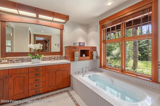 bathroom with tile patterned flooring, vanity, and a relaxing tiled tub