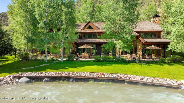 back of house featuring a patio, a water view, and a lawn