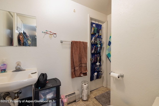 bathroom with a baseboard heating unit, sink, and tile patterned floors