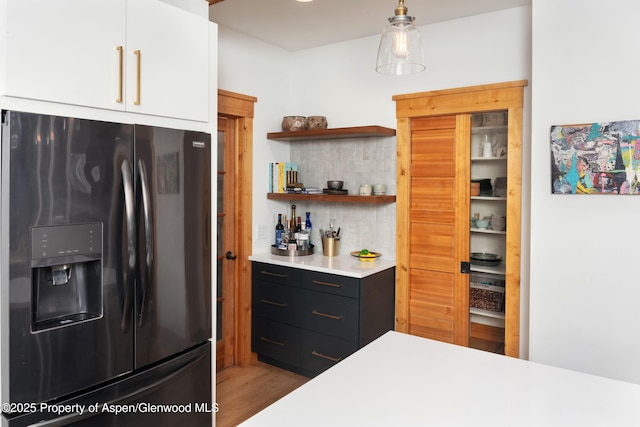 kitchen featuring fridge with ice dispenser, decorative backsplash, white cabinets, wood finished floors, and light countertops