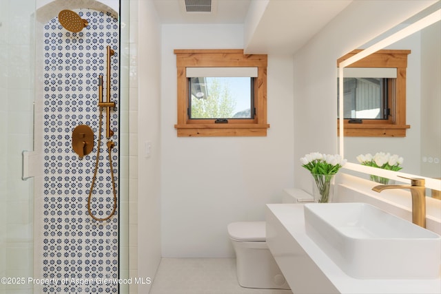 full bath with a sink, toilet, and tiled shower