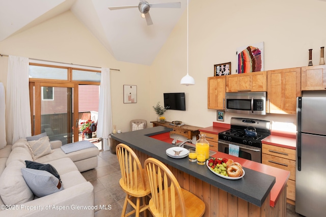 kitchen with appliances with stainless steel finishes, dark countertops, high vaulted ceiling, a breakfast bar, and a ceiling fan