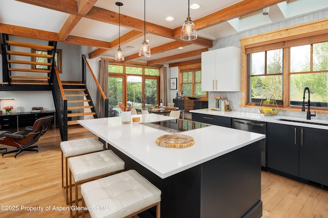 kitchen with a sink, black electric stovetop, light wood-type flooring, dark cabinetry, and light countertops