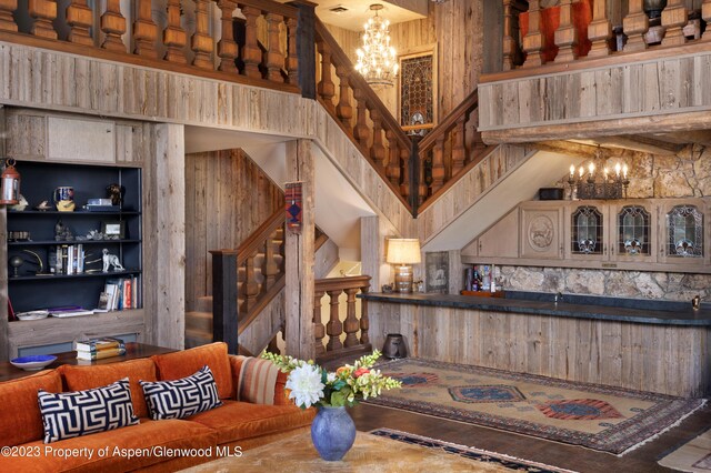 dining space with wood walls, a chandelier, and a high ceiling