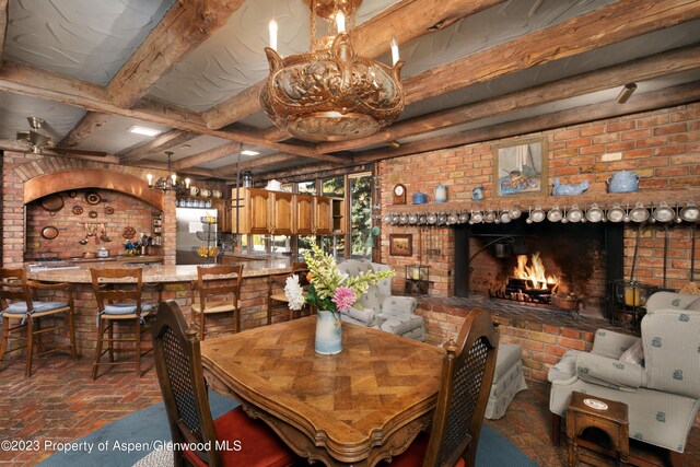 dining room with beamed ceiling, brick wall, and a brick fireplace